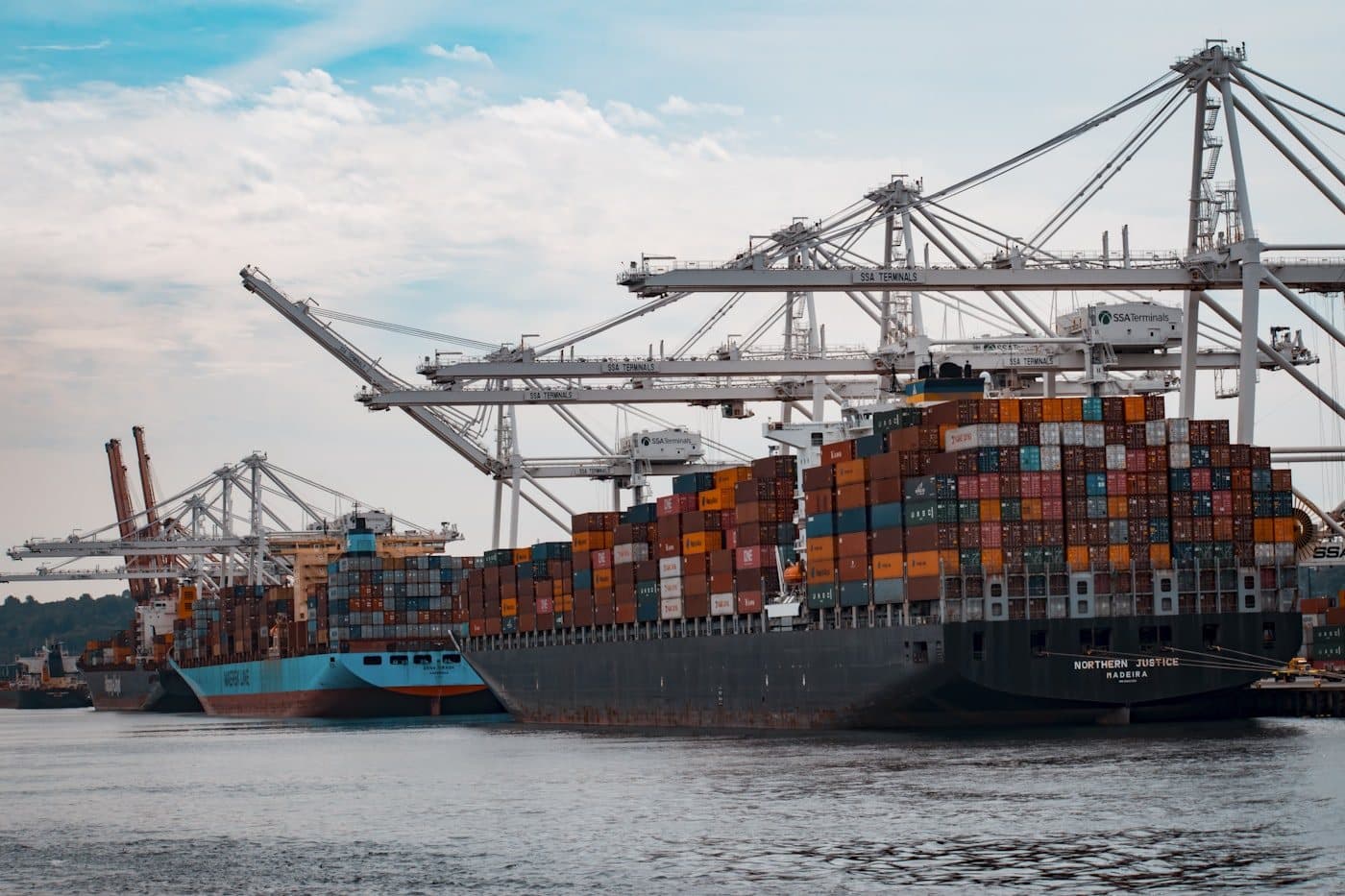 Industrial harbor with stacks of cargo shipping containers and port cranes